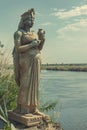 A solitary statue of Isis stands at the edge of the Nile, holding an amulet, a guardian of ancient Egyptian mysteries