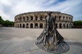 Solitary statue standing in the foreground of a large arena: des Arenes, Nimes France Royalty Free Stock Photo