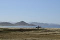 Solitary surfer carrying surf board walks along beach on coast Baja Californ