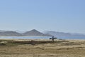 Solitary surfer carrying surf board walks along beach on coast Baja Californ Royalty Free Stock Photo