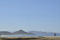 Solitary surfer carrying surf board walks along beach on coast Baja Californ