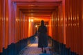 Solitary Wanderer in Traditional Japanese Torii Gates Tunnel at Dusk Royalty Free Stock Photo