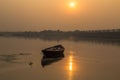 Solitary wooden boat at sunset in the water of river Damodar.