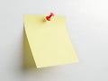 A solitary yellow sticky note pinned to a white surface with a red pushpin, ready for use Royalty Free Stock Photo