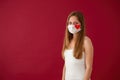 Solitary young Caucasian woman smiling under white face mask with red heart sign