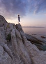 Solitude girl watching sunset high up on cliff by sea Royalty Free Stock Photo