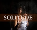 Solitude written on virtual screen. hand of young woman melancholy and sad at the window in the rain. Royalty Free Stock Photo