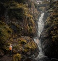 Solo Female Backpacker with orange backpack exploring waterfalls