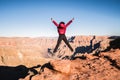 Solo girl traveler spreading her arms and jumping on the edge of a cliff inspired by the scenic view of Grand Canyon West Rim, Royalty Free Stock Photo