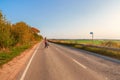 Solo journey concept. Back view of woman with backpack crosses the autumn country road, hiking trip Royalty Free Stock Photo