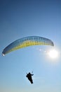 Solo paraglider is flying against the sun on a blue sky on a sunny day in Hungary