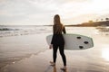 Solo Surfer. Young Woman In Wetsuit Carrying Surfboard Going Into Ocean Royalty Free Stock Photo