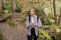 Solo tourist Woman with paper map hiking on footpath in spring forest. Person in sport clothes walking on nature Royalty Free Stock Photo