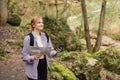 Solo tourist Woman with paper map and smartphone hiking on footpath in spring forest. Person in sport clothes walking on Royalty Free Stock Photo
