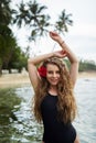 Woman with red hibiscus in hair swims in sea at tropical destination. Solo traveler enjoys serene beach getaway Royalty Free Stock Photo