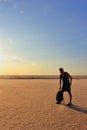 Solo traveling man with backpack in a desert at the sunset with sky background