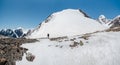 Solo trekking in the mountains. A male hikers down the mountain path. In the background, large snow-capped mountains. Copy space,