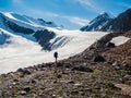 Solo trekking in the mountains. A male hikers down the mountain path. In the background, large snow-capped mountains