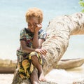 Solomon Island, shy girl with blond hair and dark skin sitting on tree trunk, South Pacific Ocean.