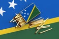 Solomon Islands flag is shown on an open matchbox, from which several matches fall and lies on a large flag