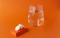 Soluble tablets and a glass of water on an orange background.