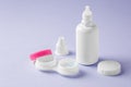 Solution bottle with contact lens in container on pastel purple background