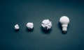 Solution and development ideas concepts with lightbulb and papaer crumpled ball on dark background Royalty Free Stock Photo