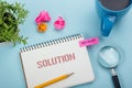 Solution. Notepad with message, pencil, coffee cup and flower. Office supplies on desk table top view.