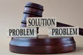 SOLUTION, PROBLEM, PROBLEM - words on wooden blocks against the background of a judge\'s gavel with a stand