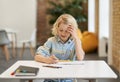 Solve equation. Diligent elementary school boy doing sums, writing in his notebook while sitting at the desk in Royalty Free Stock Photo