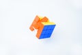 A solved rubik`s cube on a white background displaying bright blue orange and yellow color