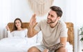 Solving problems in bed. Smiling man holding in hand blue pill, woman looking at husband Royalty Free Stock Photo