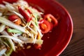 Som tam thai, green papaya salad and spicy in red plate on wooden background, Thai food or Northeastern food Royalty Free Stock Photo