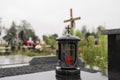 Somber cemetery scene with lantern and cross on a cloudy day Royalty Free Stock Photo