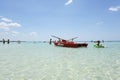 Some bathers swim in the clear and transparent waters of the Salento region in Italy - Rescue rowing boat floating in the shallow