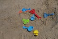 Some beach toys are made of plastic scattered randomly on the beach sand.