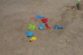 Some beach toys are made of plastic scattered randomly on the beach sand.