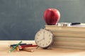 Some books and a pencil holder on a wooden table. Red apple is standing on the books. Royalty Free Stock Photo