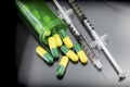 Some capsules green and yellow out of a boat together with syringes