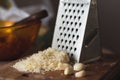 Some cheeseand garlic on a wooden breadboard. Grater.