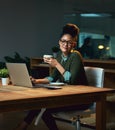 Some coffee to keep me company. Portrait of an attractive young woman working on her laptop in the office. Royalty Free Stock Photo