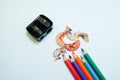 Some colored pencils of different colors and a pencil sharpener and a pencil shaving on white paper background Royalty Free Stock Photo