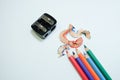 Some colored pencils of different colors and a pencil sharpener and a pencil shaving on white paper background Royalty Free Stock Photo