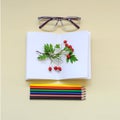 Some colored pencils with glases, a notebook and berries