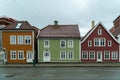some colorful wooden buildings on the side of a road with white windows