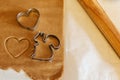 Some cookies cutter shapes on raw cookie dough, one with heart shape, another one - squirrel. Wooden roller on the table. Holiday