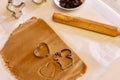 Some cookies cutter shapes on raw cookie dough, one with heart shape, another one - squirrel. Wooden roller on the table. Holiday