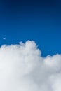 Some fluffy clouds high up and a plane in the distance