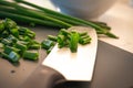 Some freshly cut green onions on a black cutting board with knife with black handle