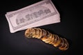 Some gold coins are lying next to a stack of 100 dollar banknotes Royalty Free Stock Photo